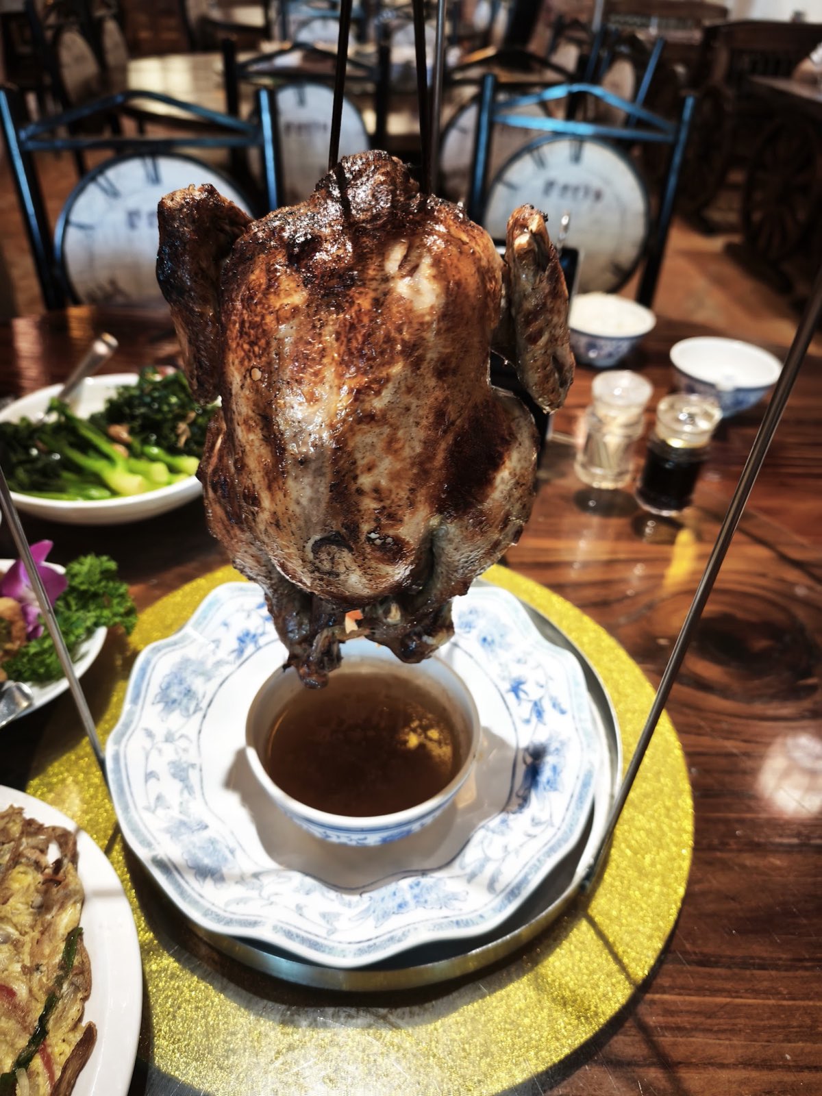 Half Acre's signature roasted Taiwanese chicken, hung whole on a rack above a bowl of house dipping sauce