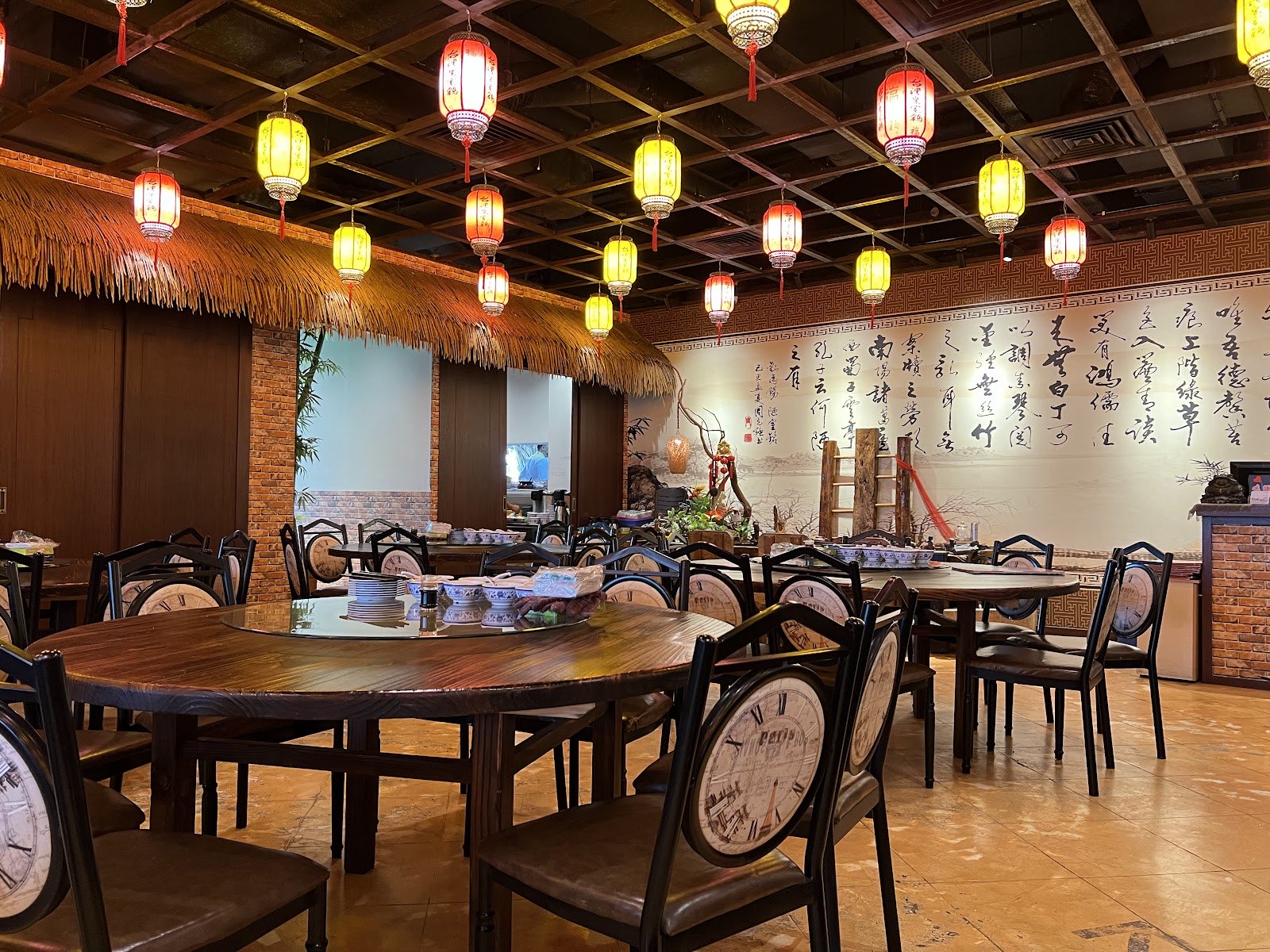 The main dining hall at Half Acre Restaurant, hung with red lanterns over round tables against a calligraphy wall