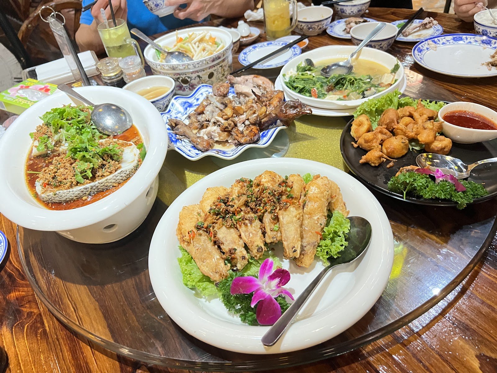 An overhead banquet spread at Half Acre with steamed fish, fried prawns and crab on a round table