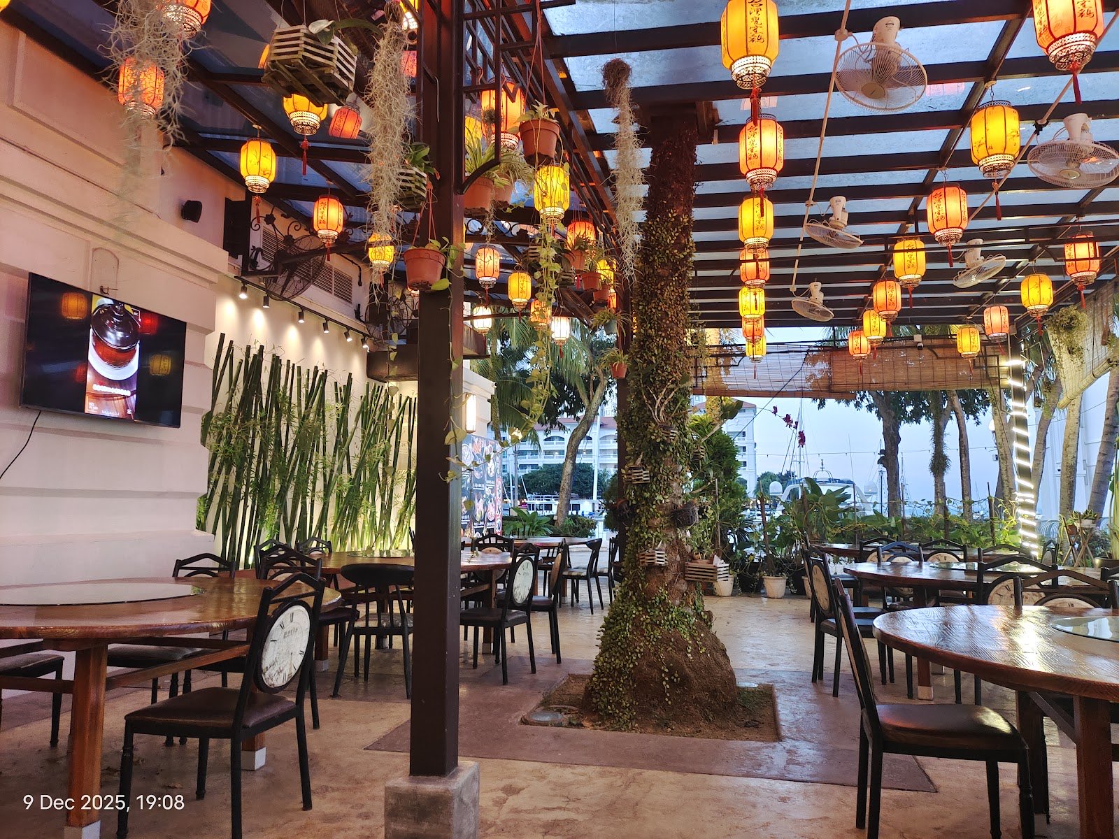 The covered waterfront terrace at Half Acre, strung with hanging lanterns and overlooking the Straits Quay marina